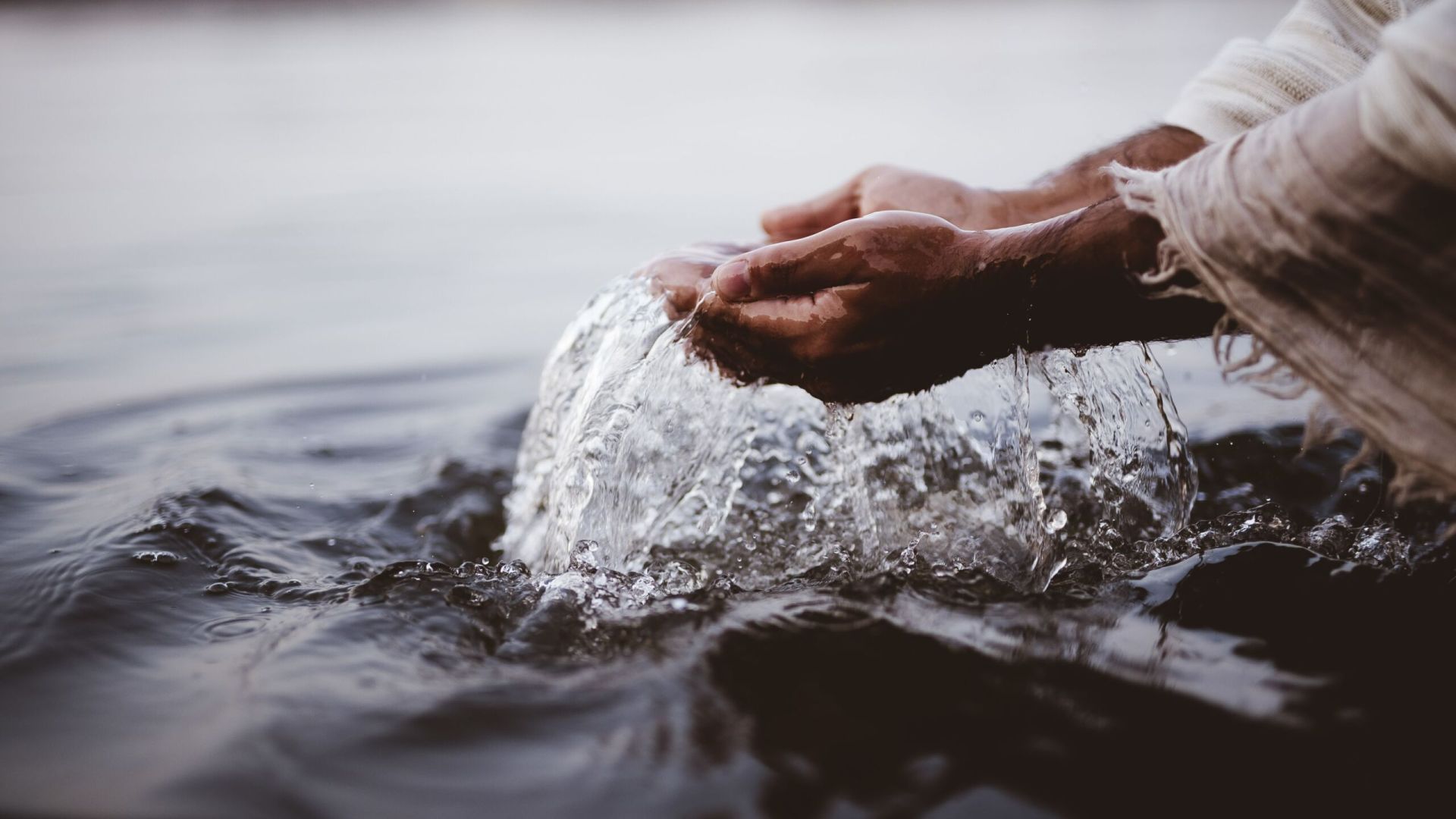 A closeup shot of a person's hands holding water wit ha blurred background