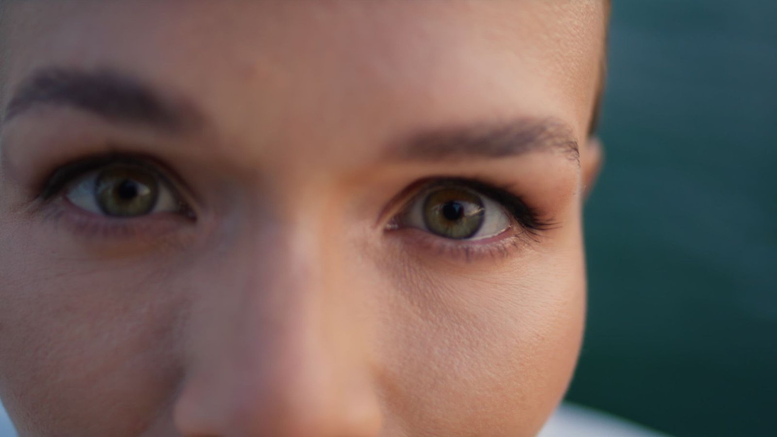 Closeup focused woman gaze staring in camera. Beautiful middle-aged woman with dark eyes posing outdoors. Gorgeous lady with natural makeup looking aside. Portrait of confident attractive female face.